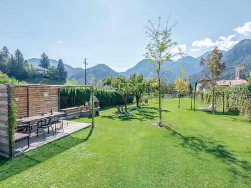 a garden with a table and chairs and mountains in the background at Apartment in Mezzolago with Lake Ledro Views in Mezzolago