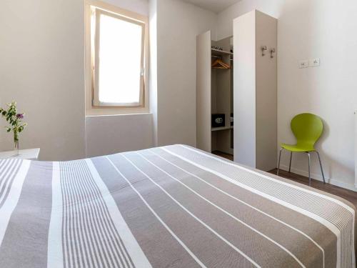 a bedroom with a large bed and a green chair at Apartment in Mezzolago with Lake Ledro Views in Mezzolago