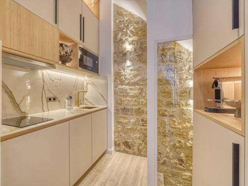 - une cuisine avec des placards blancs et un mur en pierre dans l'établissement Central historic loft by architect, near Louvre, à Paris