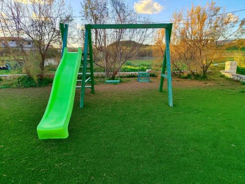 a playground with a green slide in a park at BlueTel Lixouri in Lixouri