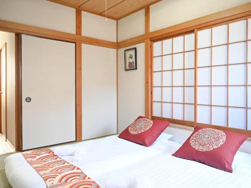a room with a bed with two red pillows at Two bathrooms, two toilets 6 mins walking distance from Keisei Takasago Station in Tokyo