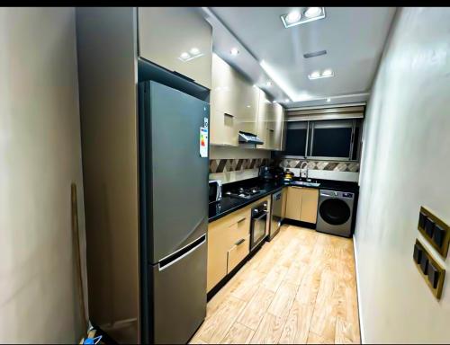 a kitchen with a stainless steel refrigerator and wooden floors at Appartement d'luxe agadir Centre in Agadir
