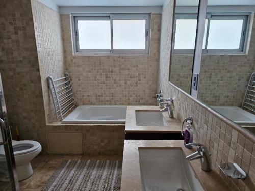 CupecoyにあるThe Cliff Sint Maarten Heavenのバスルーム(洗面台2台、バスタブ、トイレ付)