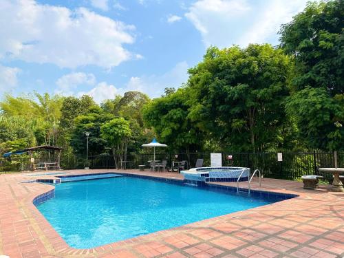 a large swimming pool in a yard with trees at Beautiful house with a pool in Pereira in Pereira