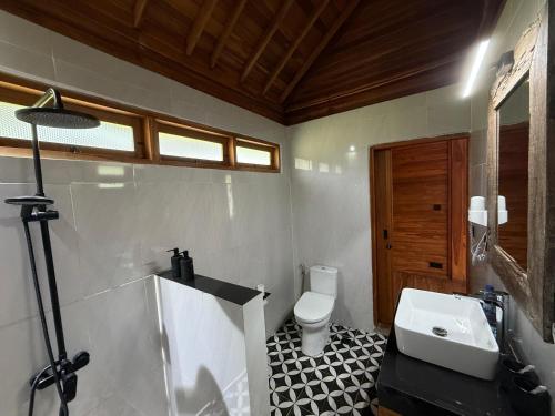 a bathroom with a white toilet and a sink at Taman Swarga Villa Resort & Spa Sidemen in Sidemen
