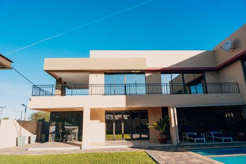 a large white house with a balcony at Escapade Lux Guesthouse in Gaborone