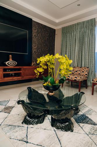 a living room with a vase with yellow flowers on a table at Escapade Lux Guesthouse in Gaborone