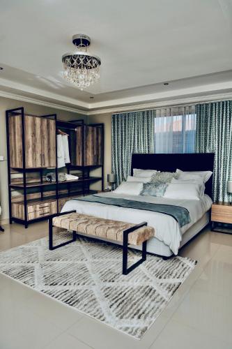 a bedroom with a large bed and a chandelier at Escapade Lux Guesthouse in Gaborone