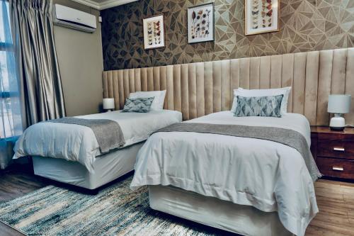 two beds in a hotel room with at Escapade Lux Guesthouse in Gaborone