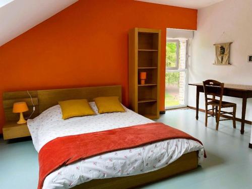 a bedroom with an orange wall with a bed and a desk at Gîte spacieux, confort moderne, nature et tranquillité près de Tours et des châteaux de la Loire - FR-1-381-273 in Le Boulay