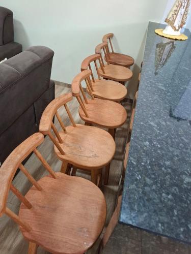 a row of wooden chairs sitting next to a table at Casa Alice e Matheus in Olímpia
