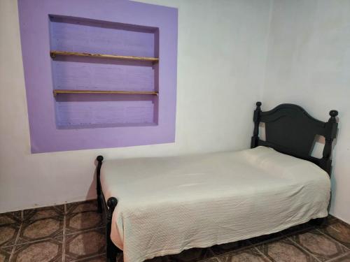 a bed in a room with a purple window at Hostal Nahiara, Iruya in Iruya