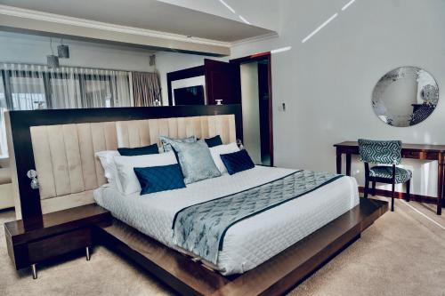 a bedroom with a large bed and a desk at Escapade Lux Guesthouse in Gaborone