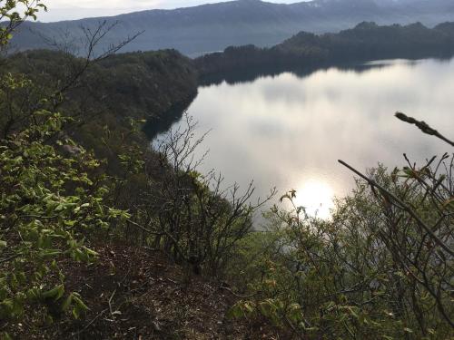 a view of a lake with the sun shining on the water at Towadako Hostel in Towada