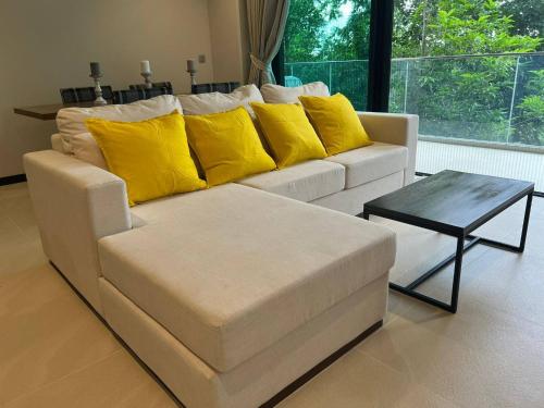 a white couch with yellow pillows and a coffee table at InterContinental Khao Yai Condo with 2Bedrooms, 2Bathrooms plus 3 bicycles Free in Pong Talong