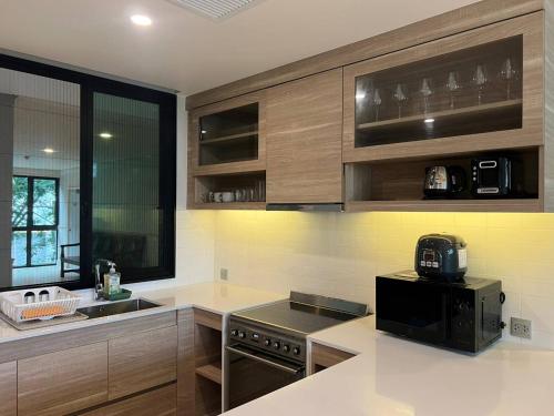 a kitchen with wooden cabinets and a black appliance at InterContinental Khao Yai Condo with 2Bedrooms, 2Bathrooms plus 3 bicycles Free in Pong Talong