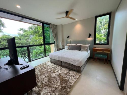a bedroom with a bed and a tv and windows at InterContinental Khao Yai Condo with 2Bedrooms, 2Bathrooms plus 3 bicycles Free in Pong Talong