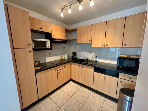 une cuisine avec des placards en bois et des comptoirs noirs dans l'établissement T2 avec terrasse, 500m de la plage, Les Sables-d'Olonne - FR-1-92-896, à Les Sables-dʼOlonne