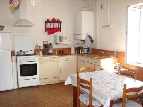 La cuisine est équipée d'une table et de plaques de cuisson blanches. dans l'établissement Maison spacieuse à Barbâtre, près de la plage - FR-1-823-159, à Barbâtre