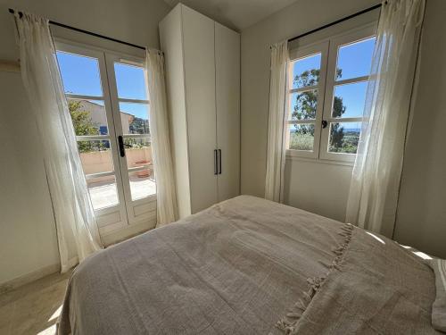 - une chambre blanche avec deux fenêtres et un lit dans l'établissement Maison rénovée 2 chambres, terrasse vue mer - FR-1-726-63, à La Croix-Valmer