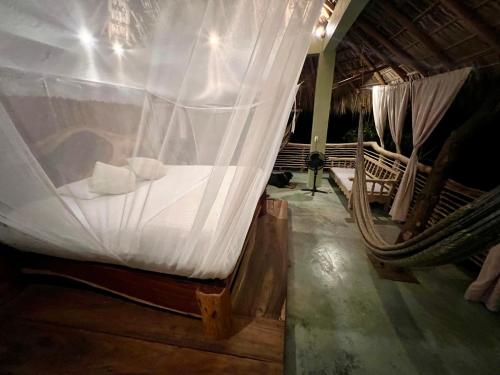 a bedroom with a bed with a mosquito net at Habitaciones en casa De los árboles en la playa con alberca in Arroyo Cruz