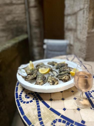 une assiette d'huîtres sur une table avec un verre de vin dans l'établissement Maison de la Gargoyle, à Pézenas