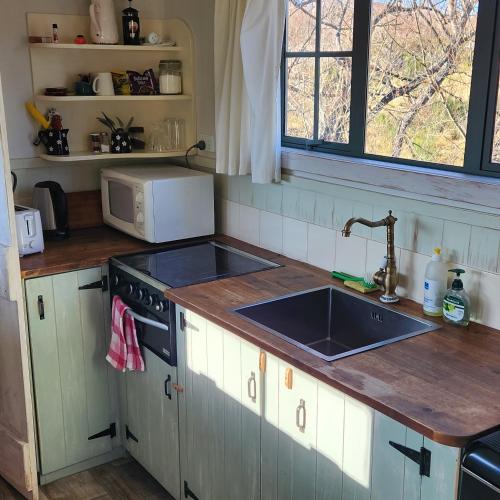 a kitchen with a sink and a stove and a window at Shepherds Hut Gateway to Tekapo and the MacKenzie District in Burkes Pass