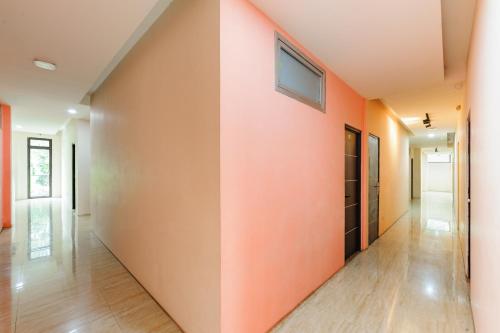 an empty hallway with orange walls and wooden floors at Bubulak Inn by Ruang Tidur in Kedungbadak