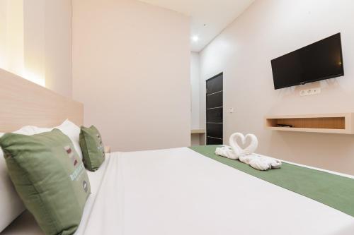a bedroom with a white bed with a flat screen tv at Bubulak Inn by Ruang Tidur in Kedungbadak