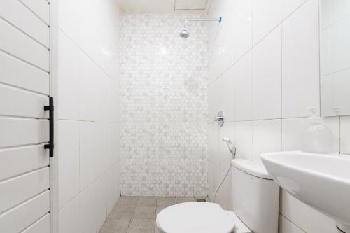 a white bathroom with a toilet and a sink at Bubulak Inn by Ruang Tidur in Kedungbadak