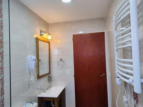 Un baño con lavabo y puerta de madera. en Apart Ruta 40, en El Chaltén