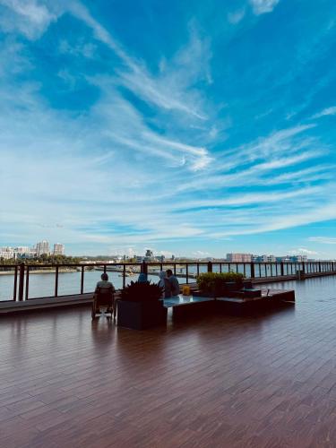two people sitting in chairs on a boardwalk near the water at R&F PRINCESS COVE BY HOMEFORT SUITES in Johor Bahru