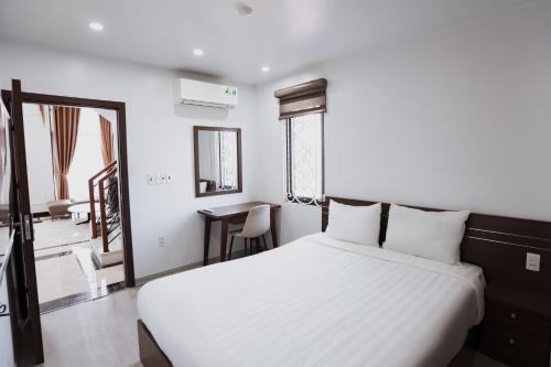 a bedroom with a large white bed and a desk at The Eastern Hotel & Apartment in Hai Phong