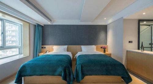 a bedroom with two beds with blue blankets and a window at Xian Katie Eastman Hotel in Xi'an