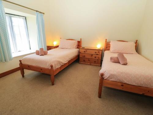 zwei Einzelbetten in einem Zimmer mit Fenster in der Unterkunft Keepers Cottage in Blandford Forum