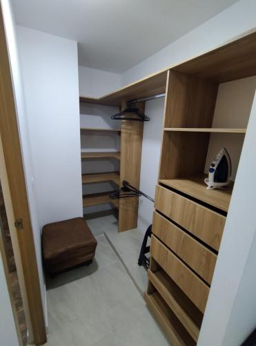 a walk in closet with wooden shelves and a stool at Moderno apto cómodo bien ubicado in Floridablanca