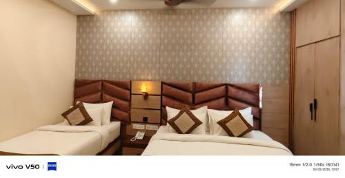 a hotel room with two beds and a headboard at Hotel Mantavya in Kakarmatha