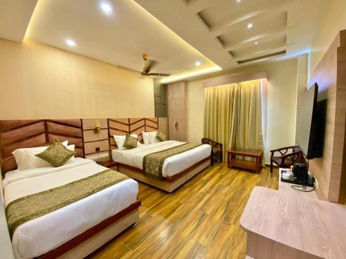 a hotel room with two beds and a flat screen tv at Hotel Mantavya in Kakarmatha