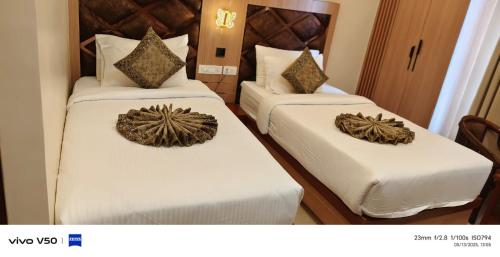 two beds in a hotel room with white sheets at Hotel Mantavya in Kakarmatha