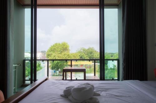a bed with a teddy bear on it in front of a window at Triple O Phala Beach in Ban Phala