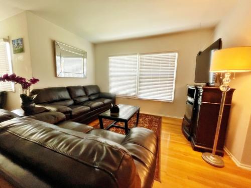 a living room with a leather couch and a television at Cozy Beautiful Private Home in Prime Location in Glendora