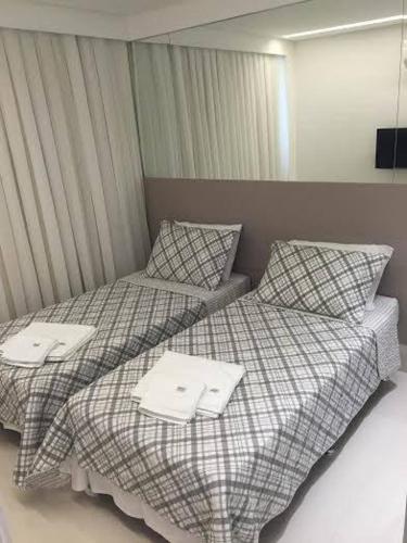 two beds in a hotel room with towels on them at Malawi Resort Essence in Porto De Galinhas