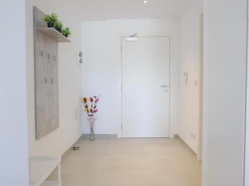a white hallway with a door and a vase of flowers at Paceville StJulians centre near Beach in Paceville