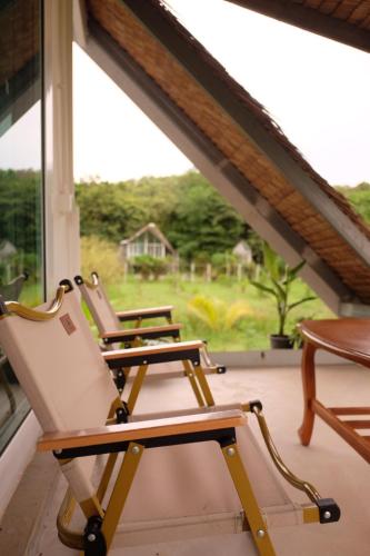 two chairs sitting on a porch with a window at Royal mountain lake view in Ratchaburi