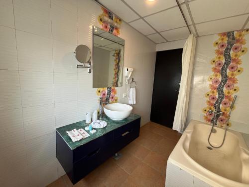 a bathroom with a sink and a mirror and a tub at Landmark Narayani in Chitwan