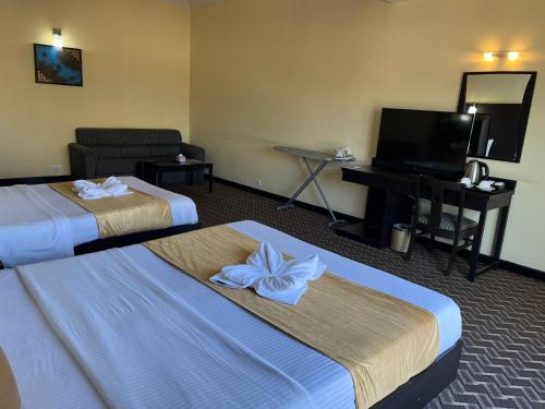 a hotel room with two beds and a flat screen tv at Landmark Narayani in Chitwan