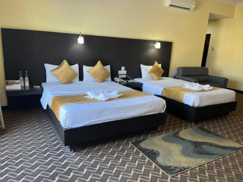 a hotel room with two beds and a chair at Landmark Narayani in Chitwan