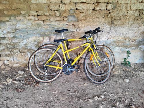 a yellow bike parked next to a stone wall at LE LOGIS DE LA PIERRE in Périgné