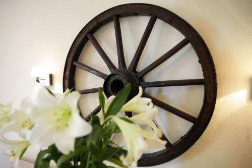 a wooden wheel on a wall with white flowers at Motel Højmølle Kro in Eskilstrup