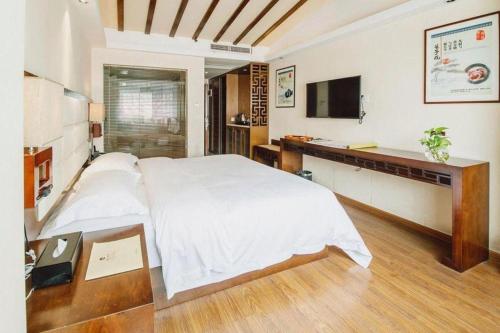 a bedroom with a bed and a desk and a television at Oriental Hotel in Dongguan